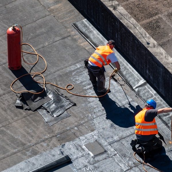 Birds eye view of a roof construction site. Professional bitumen waterproofing on a flat building.